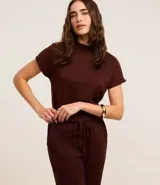 Blusa de mujer color marrón oscuro con textura acanalada, cuello alto y mangas cortas.