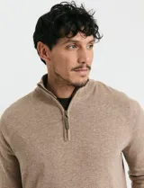 Remera de punto con medio cierre frontal, manga larga, cuello y puños en tejido canalé. Presenta un diseño con cierre metálico y detalle de puller en tono oliva.