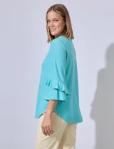 Blusa celeste de tejido piqué con mangas 3/4 y volados en los puños.