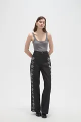 Pantalon de jean negro de corte ancho y tiro alto, con estampado de rombos en los laterales de las piernas.