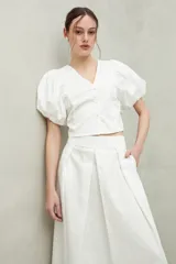 Falda larga de algodón blanca, con corte amplio y fluido, y una tabla central profunda que estiliza la figura.