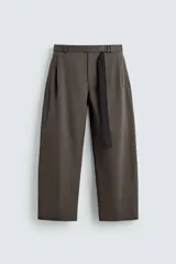 Pantalón de corte wide fit confeccionado en tejido con algodón. Presenta pliegues frontales, cintura ajustable con cinturón integrado, bolsillos laterales y bolsillos traseros de vivo. Cierre frontal con cremallera y botón.