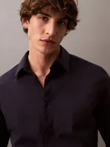 Camisa de manga larga Calvin Klein con corte slim, cuello clásico estructurado y cierre frontal con botones a tono. Presenta un diseño minimalista con monograma bordado en el pecho.