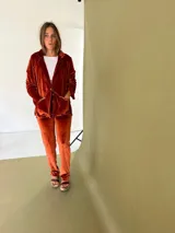 Blazer de terciopelo color terracota, con cuello solapa, cierre con botón de guampa y detalles en cuero. Corte entallado.