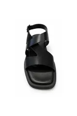 Sandalias planas de cuero color negro, con tiras cruzadas en el empeine, diseño abierto y tira en el talón con hebilla metálica dorada para ajuste.