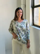 Sweater de punto con estampado animal print en tonos verde claro y gris sobre fondo beige, de cuello redondo y manga larga.