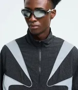 Campera liviana de poliamida con diseño cuadrillé sutil, cuello alto y cierre frontal. Presenta paneles reflectivos estratégicos para mayor visibilidad, puños elásticos y corte contemporáneo.