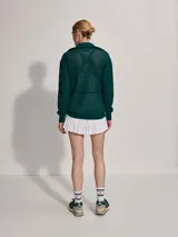 Sweater de punto verde oscuro con cierre dorado y cuello polo. Presenta un diseño en V blanco en el pecho.