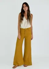 Pantalón acampanado color amarillo mostaza, de tiro alto y corte holgado.