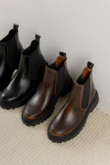 Botas tipo Chelsea de cuero con acabado vintage, diseño de caña media con paneles elásticos laterales y suela track robusta.