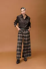 Pantalón de corte ancho y tiro alto con estampado de cuadros en tonos marrones, negros y beige. Presenta pinzas en la cintura y bolsillos laterales.