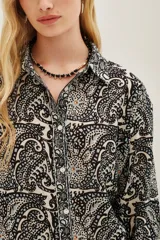 Camisa de algodón con estampado tipo paisley en tonos blanco, negro y azul. Presenta cuello clásico, cierre frontal con botones y mangas largas con puños abotonados.