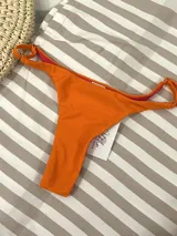 Bikini colaless color naranja, con breteles finitos regulables en los costados.