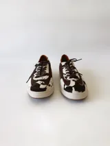 Zapatilla deportiva de cuero con estampado de vaca (pelo), color marrón y blanco. Suela blanca gruesa.