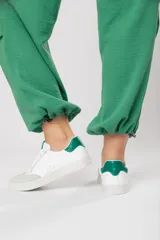Zapatillas acordonadas de cuero color blanco con puntera de gamuza gris y detalles en verde.