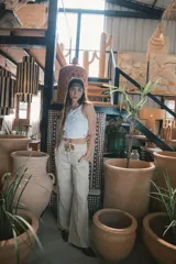 Pantalón de corte recto y tiro alto, confeccionado en lino color blanco. Presenta cierre frontal con botón y bolsillos laterales.