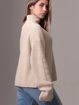 Sweater de tejido grueso con cuello alto, corte relajado y mangas largas. Presenta una textura acanalada y un diseño minimalista con etiqueta distintiva de la marca en el ruedo.