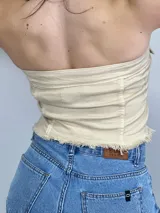 Top strapless color beige con botones plateados al frente y dos bolsillos pequeños.