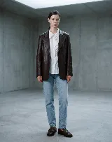 Blazer de cuero bovino color bordó, con silueta entallada, solapas clásicas y cierre frontal con un botón. Presenta mangas largas con detalles fruncidos que aportan textura.