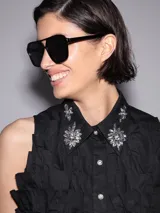 Camisa blanca sin mangas con cuello clásico, cierre frontal con botones y apliques de strass en cuello y frente.