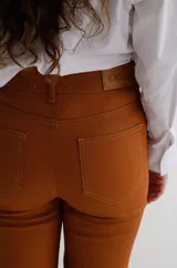 Pantalón cropped de tiro medio con acabado engomado, corte recto y bolsillos laterales. Presenta cierre frontal con botón y costuras a tono.