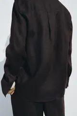 Camisa color coral confeccionada en lino 100%, de corte recto, con cuello solapa, manga larga con puños abotonados y cierre frontal con botones.