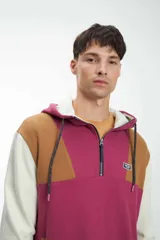 Canguro magenta con capucha, cierre parcial con cremallera, mangas largas y diseño color block en marrón, blanco y magenta.