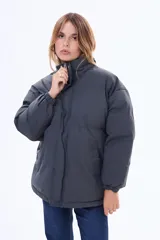 Campera puffer de corte holgado, color negro, con cuello alto, cierre frontal y puños elásticos.