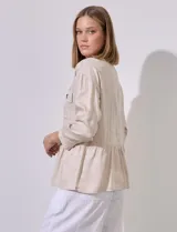 Chaqueta blanca de tencel con cuello con solapa, escote en V y abertura central con broches internos. Tiene corte en la cintura y bolsillos delanteros.