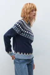 Sweater de punto en color azul marino con diseño jacquard geométrico en tonos blanco, marrón y verde en el canesú, puños y ruedo. Presenta cuello redondo y mangas largas.