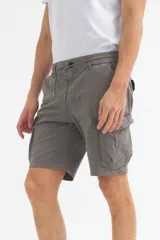 Bermuda cargo color gris oscuro, confeccionada en gabardina con efecto teñido. Presenta pretina elástica con cordón de ajuste, bolsillos laterales y bolsillos cargo con solapa en las piernas.