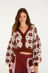 Cardigan de punto con escote en V, cierre frontal con botones y mangas largas abullonadas, con diseño estampado geométrico en tonos marrón, lila y crudo.