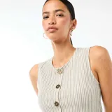 Camiseta de tirantes blanca con rayas sutiles, cuello redondo y cierre frontal de botones metálicos dorados martillados, con abertura inferior.