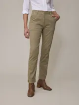 Pantalón de vestir color beige, de corte recto, con bolsillos laterales y traseros. Se ajusta a la cintura con botón y cierre. El ruedo tiene un botón decorativo.