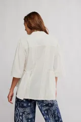 Blusa blanca con cuello mao y escote en V, de manga corta y corte amplio con fruncido frontal.