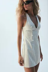 Vestido mini Zara de rayas diplomáticas, con escote en pico, diseño sin mangas, doble botonadura frontal decorativa y cierre lateral con cremallera oculta.