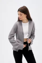 Saco de punto gris con cuello en V, cierre frontal con botones y mangas largas con puños anchos decorados con botones.