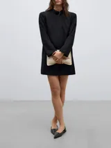 Vestido mini de línea recta en color negro, con cuello solapa y manga larga. Presenta un diseño minimalista y estructurado.