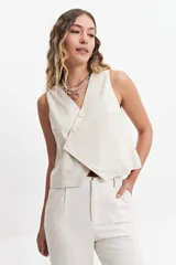 Chaleco corto color marrón topo, con escote en V asimétrico y cierre cruzado con botones.