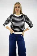 Buzo de punto fino con diseño de rayas horizontales en negro y blanco, cuello redondo, mangas largas y puños y ruedo en tono liso.