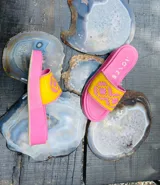 Sandalias tipo chinelas de cuero color suela, con plataforma baja y diseño de capellada con calados geométricos inspirados en motivos pampeanos.