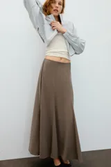 Falda larga de tiro alto, color negro, con diseño fluido y cintura elástica. Cierre lateral con cremallera oculta en costura.