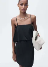 Vestido corto negro de tirantes finos, escote recto y corte ajustado. Presenta un volante superpuesto en el pecho.