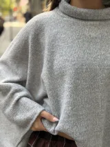 Poncho de hilo liviano en color gris, con cuello alto y diseño de caída fluida y asimétrica.