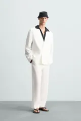 Pantalón de corte relajado confeccionado en tejido de lino. Presenta cintura elástica, bolsillos frontales, bolsillo trasero de vivo y cierre frontal con cremallera y botón.