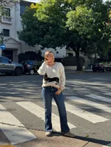 Sweater tejido color crema con cuello y puños acanalados en color naranja. Presenta un diseño bordado de un perro salchicha negro con un moño naranja.