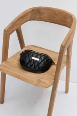 Riñonera Urban Haus de diseño acolchado con patrón de rombos, color negro, con cierre superior y placa metálica dorada con el logo de la marca en el frente.