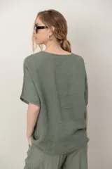 Blusa de lino color blanco, de corte amplio, con escote redondo, mangas cortas y detalle de guarda calada horizontal en la parte inferior.