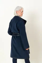 Tapado azul marino de lana y cashmere, con cuello solapa, bolsillos delanteros y cinturón de cuero negro.