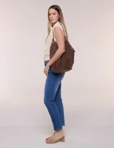Cartera tipo hobo de gran capacidad confeccionada en símil gamuza color marrón, con diseño relajado, base sólida reforzada y ribete de cuerina a juego en los bordes. Cuenta con una sola asa de hombro y un compartimento interior independiente.